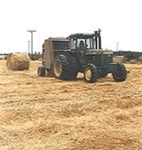 Tractor pulling straw baler in the field